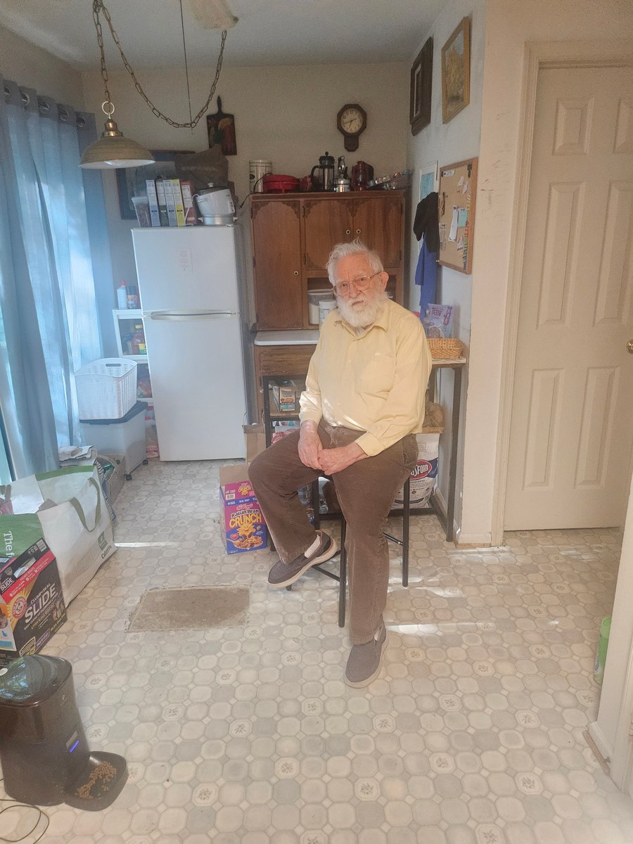Grandfather posing in a kitchen wearing a pale yellow shirt