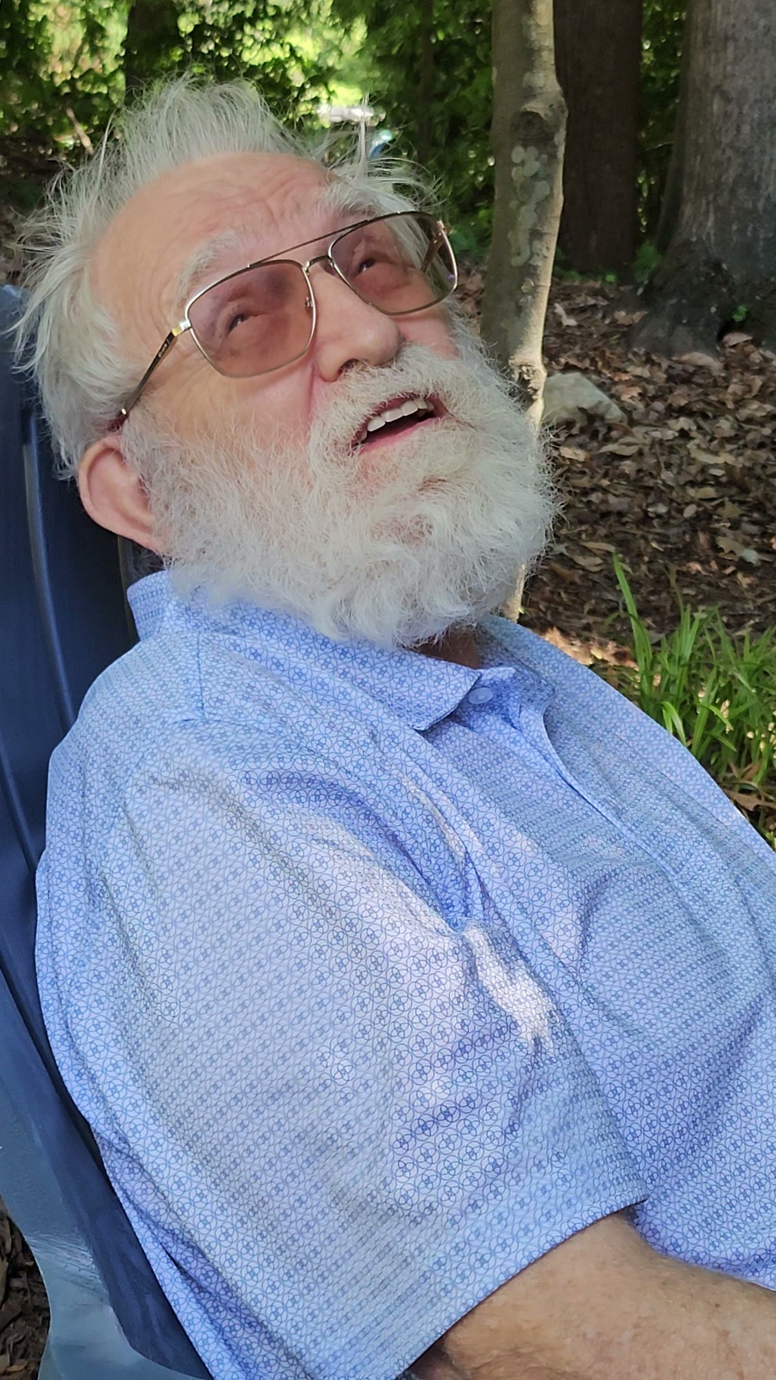 Grandfather looking upward outdoors in his blue shirt, with eyes and mouth open