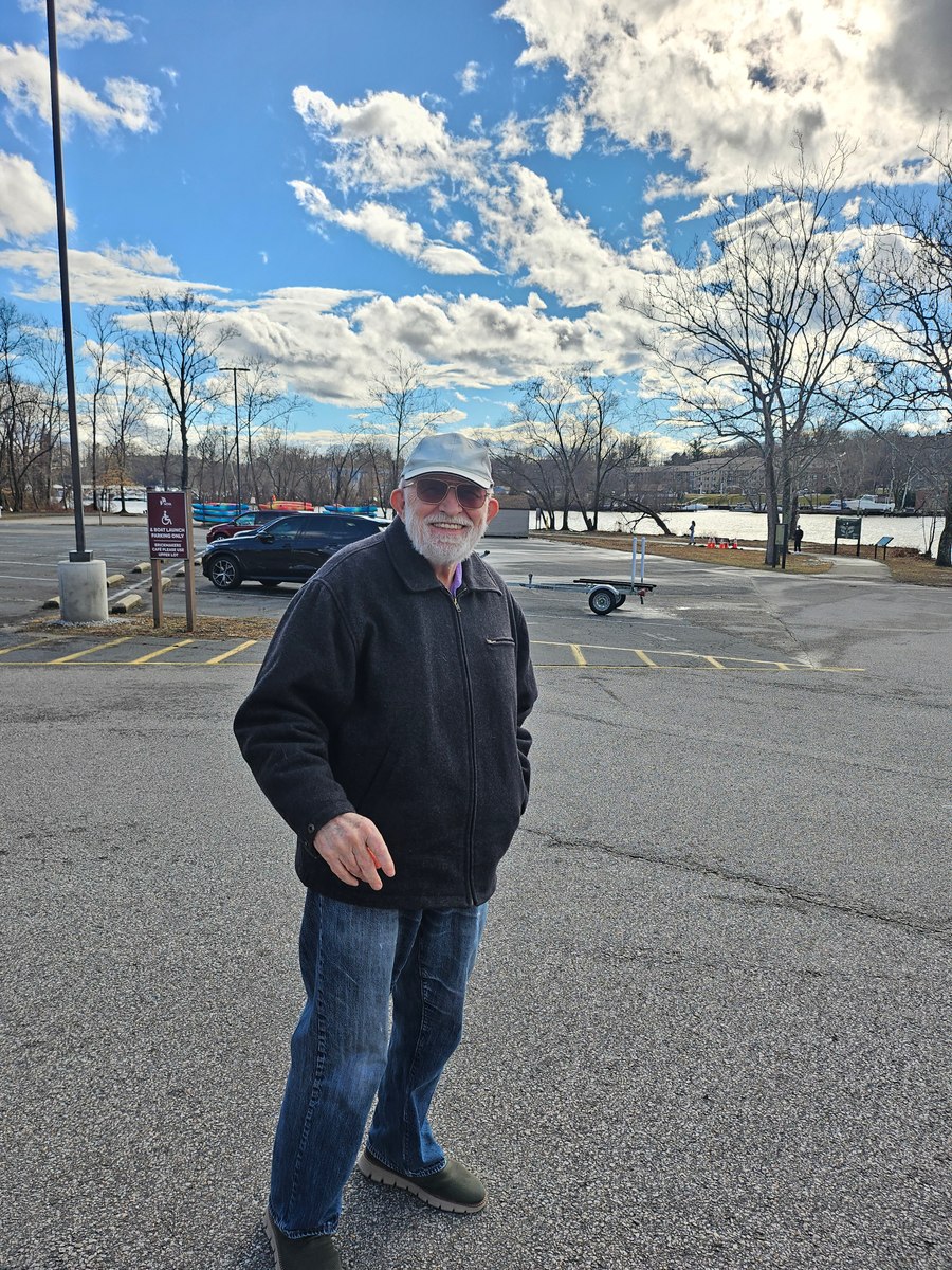 Grandfather standing outdoors in a dark jacket beneath a bright sky